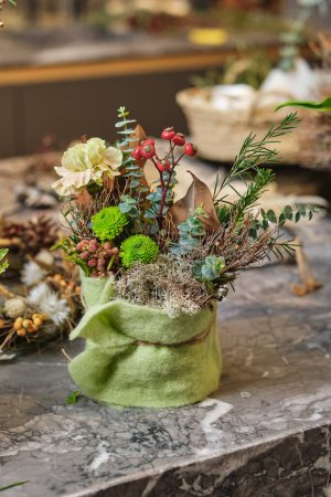 Téléchargez les photos : Bouquet de diverses fleurs fraîches et herbes placées en pot décoré de tissu vert sur table en marbre - en image libre de droit