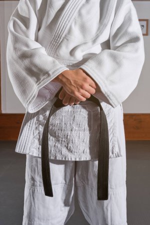 Téléchargez les photos : Personne méconnaissable portant le kimono debout dans la pièce lumineuse avec les mains croisées - en image libre de droit