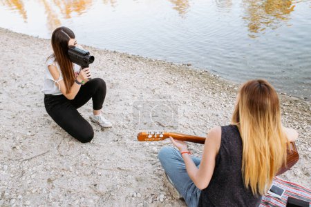 Photo for Young woman shooting friend playing guitar - Royalty Free Image