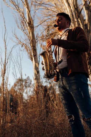 Téléchargez les photos : Jeune musicien jouant du saxophone au coucher du soleil - en image libre de droit