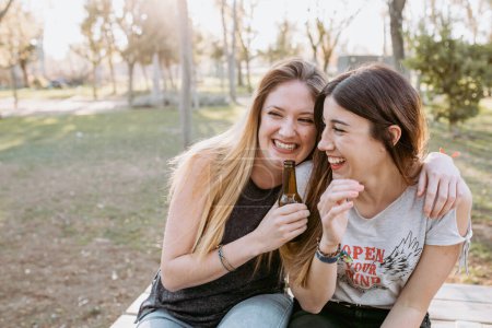 Téléchargez les photos : Filles amies embrasser et rire dans le parc - en image libre de droit
