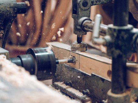 Téléchargez les photos : Machine métallique professionnelle pour couper le trou de forage en bois dans les détails en bois contre le tas de bois dans la campagne sur fond flou - en image libre de droit