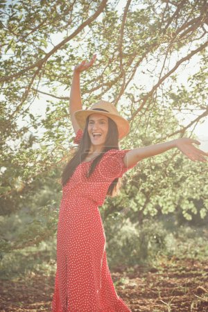 Photo for Side view of beautiful young female in summer dress and hat on sunny day - Royalty Free Image