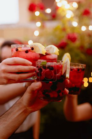 Foto de Grupo de amigos cosechas tintineo vasos con coloridas bebidas de bayas en la fiesta del patio de verano - Imagen libre de derechos