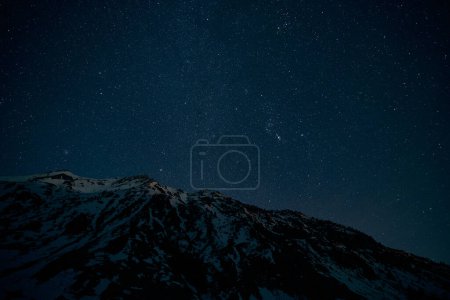 Photo for From below breathtaking mountain range covered with snow against dark starry sky at night in countryside - Royalty Free Image