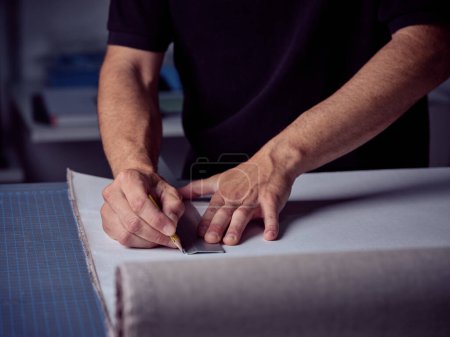 Crop encuadernador masculino haciendo marcas en el papel mientras se utiliza el lápiz y la regla y trabajando en el banco de trabajo en el taller