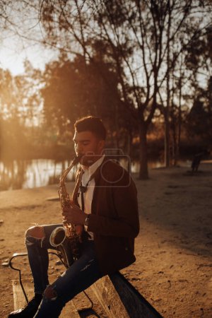 Téléchargez les photos : Jeune musicien jouant du saxophone au coucher du soleil - en image libre de droit