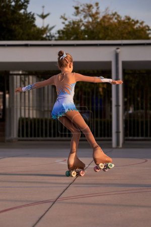 Foto de Vista trasera de cuerpo completo de chica anónima en maillot montando patines quad en el patio de recreo en el soleado día de verano en la ciudad - Imagen libre de derechos