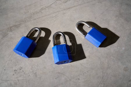 Photo for High angle of set of secure blue unbreakable padlocks placed on gray surface with scratches in sunlight - Royalty Free Image