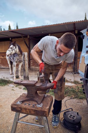 Foto de Herrero trabajando en el yunque cambiando la herradura a una pierna con herramientas - Imagen libre de derechos