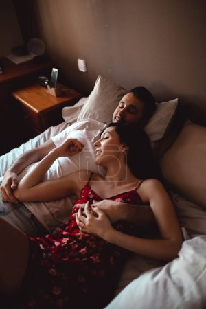 Photo for Happy couple cuddling on bed - Royalty Free Image