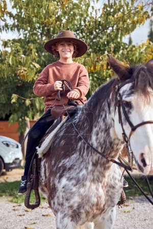 Foto de Boy en el sombrero montando su caballo marrón moteado - Imagen libre de derechos