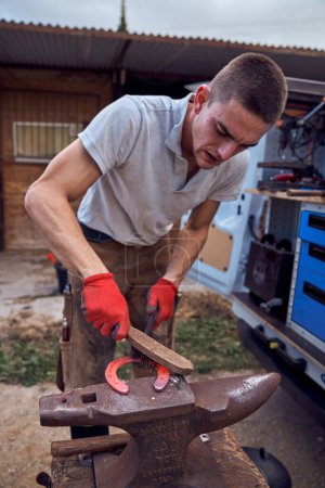 Téléchargez les photos : Forgeron travaillant sur l'enclume changer le fer à cheval à une jambe avec des outils - en image libre de droit