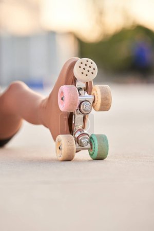 Photo for Leg of crop anonymous girl in quad roller skate with colorful wheels sitting on walkway during training in city against blurred background - Royalty Free Image