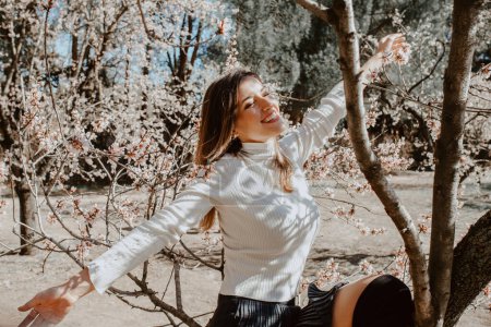 Téléchargez les photos : Jeune femme heureuse entre les arbres dans le jardin - en image libre de droit
