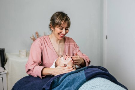 Photo for Female cosmetician applying facial cleanser on face of female client during skin care treatment in beauty salon - Royalty Free Image