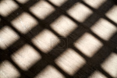 Téléchargez les photos : D'en haut de l'ombre du treillis de la fenêtre sur le sol minable le jour ensoleillé comme fond abstrait - en image libre de droit