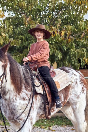 Foto de Boy en el sombrero montando su caballo marrón moteado - Imagen libre de derechos