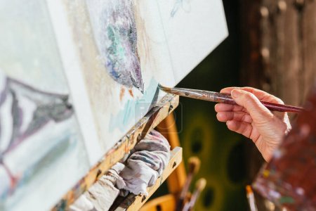 Foto de Artistas femeninas envejecidas irreconocibles recortadas pintando sobre lienzo en el patio trasero en el día soleado en verano - Imagen libre de derechos