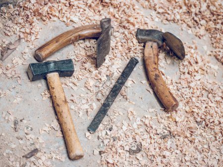 Foto de Conjunto de vista superior de herramientas y martillo antiguo adze colocado en la superficie desordenada con virutas en la zona rural del campo - Imagen libre de derechos