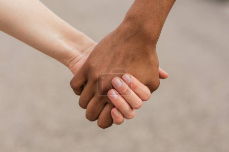 Photo for Crop anonymous multiethnic friends holding hands for unity friendship and equality concept against blurred road - Royalty Free Image