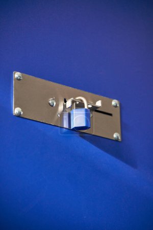 Téléchargez les photos : Une écluse verrouillée bleue sur une barrière métallique dans un entrepôt - en image libre de droit