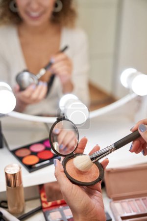 Photo for Crop unrecognizable female beauty master taking blush with professional brush while preparing applying facial makeup - Royalty Free Image