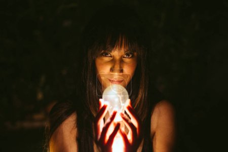 Téléchargez les photos : Femme réfléchie avec ampoule brûlante dans l'obscurité - en image libre de droit
