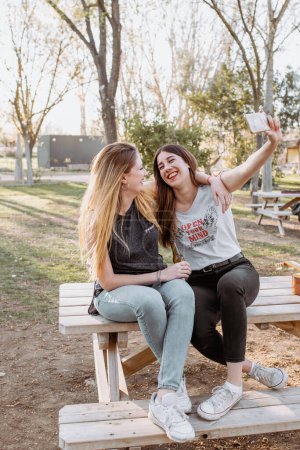Téléchargez les photos : Femmes souriantes prenant selfie dans le parc - en image libre de droit