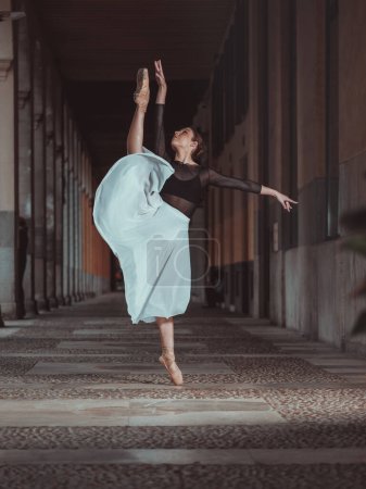 Foto de Cuerpo completo de joven bailarina de ballet flexible en zapatos puntiagudos estirándose en división vertical en pasaje - Imagen libre de derechos