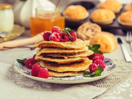 Photo for Stack of appetizing sweet pancakes served on plate with ripe raspberries and mint leaves for breakfast at home - Royalty Free Image