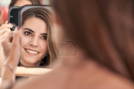 Téléchargez les photos : Optimiste jeune cliente regardant la réflexion dans le miroir avec le sourire tout en se tenant debout dans le salon de beauté de lumière moderne pendant le rendez-vous - en image libre de droit