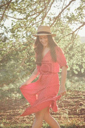 Téléchargez les photos : Femme adulte en robe d'été et chapeau en forêt le jour ensoleillé - en image libre de droit