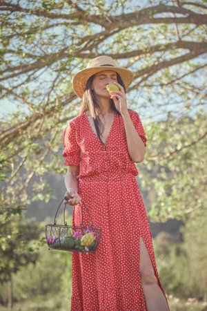 Téléchargez les photos : Dame tenant citron et profiter de la saveur le matin promenade d'été sur fond flou - en image libre de droit
