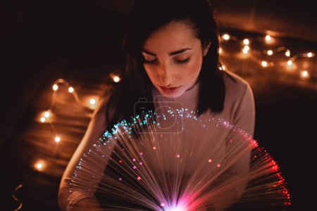 Photo for Young woman with fairy lights in darkness - Royalty Free Image