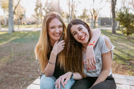 Foto de Chicas amigas abrazándose y riendo en el parque - Imagen libre de derechos