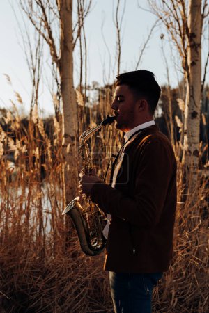Photo for Young musician playing the saxophone at sunset - Royalty Free Image