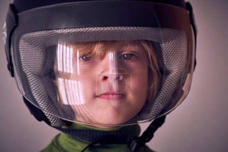 Photo for Portrait of cute little kid with blond hair and brown eyes wearing protective helmet with transparent plastic front and looking at camera - Royalty Free Image