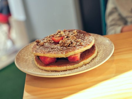 Photo for Tasty sweet pancakes with strawberries and chocolate paste sprinkled with powdered sugar served on plate on table in light cafe - Royalty Free Image