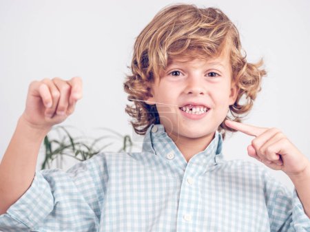 Foto de Lindo coraje preadolescente niño demostrando espasmos diente con hilo y mirando a la cámara - Imagen libre de derechos
