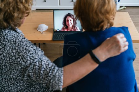 Téléchargez les photos : Femmes ayant une conversation vidéo sur ordinateur portable à la maison - en image libre de droit