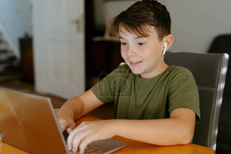 Téléchargez les photos : Enfant concentré utilisant un ordinateur portable à la maison - en image libre de droit