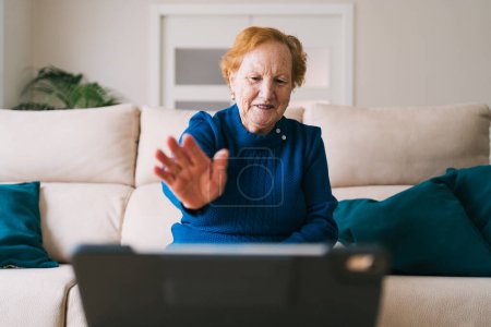 Téléchargez les photos : Femme âgée communiquant avec un ami pendant le chat vidéo sur un ordinateur portable - en image libre de droit