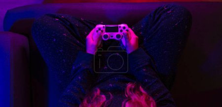 Photo for Girl's hands top view with the video game controller and colorful lights. - Royalty Free Image