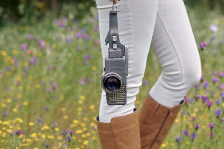 Téléchargez les photos : Photographe de cultures marchant dans le parc avec une caméra vidéo vintage - en image libre de droit