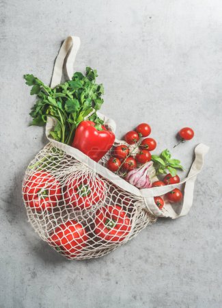 Téléchargez les photos : Vue de dessus de divers légumes et herbes dans un sac à provisions réutilisable en plastique gratuit à la table de cuisine en béton gris - en image libre de droit