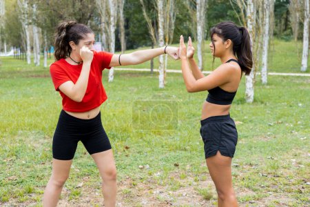Foto de Dos jóvenes boxeadoras multiétnicas entrenando al aire libre. Boxeo sparring y entrenamiento de perforación en un parque de la ciudad. - Imagen libre de derechos