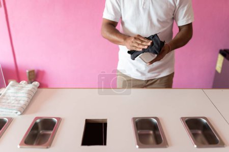 Photo for An ice-cream parlor worker is cleaning a metal flavor tray with a cleaning cloth before opening. Concept of small business - Royalty Free Image