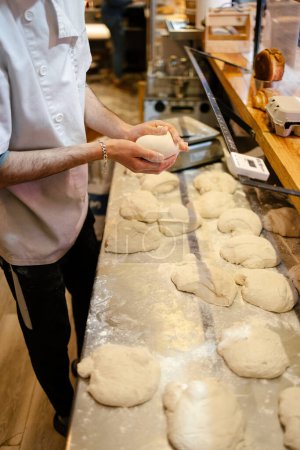 Téléchargez les photos : Plan détaillé des mains d'un boulanger méconnaissable en pétrissant manuellement sur la table d'une boulangerie - en image libre de droit