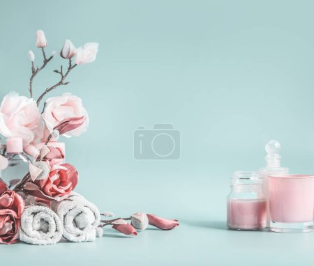 Téléchargez les photos : Fond de beauté avec des fleurs rose pastel et cosmétique au fond bleu pastel - en image libre de droit